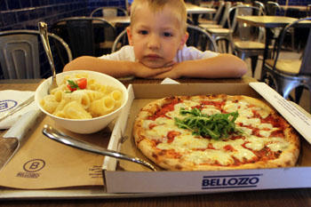 our 5-year old son with a round pizza and a bowl of pasta in Bellozzo