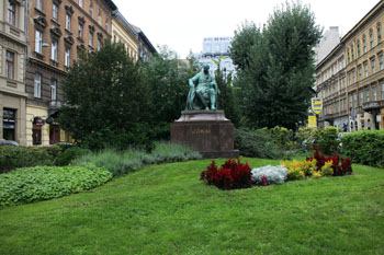 statue of Mor Jokai surrounded by flowers and green lawn
