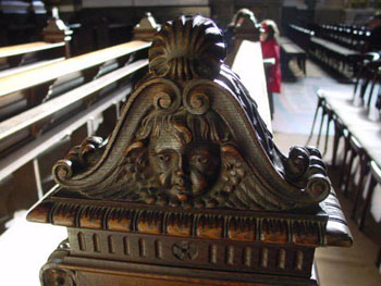 a face of anangel carved from wood on a pew