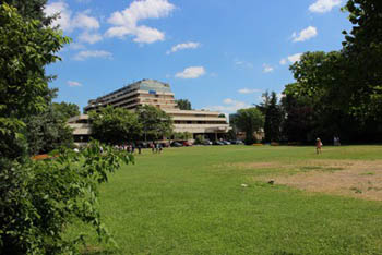 a big lawn with trees, a hotel building in the background