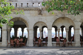 tables and chairs on the first level terrace of Halaszbasty Resturant, the view of Paliament in the background