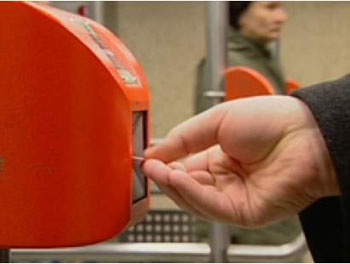 a hand inserting a ticket into an orange ticket validation machine
