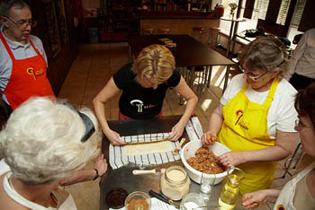 a young woman rolling up strudel dough 3-4 other students watching her