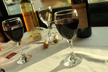 3 glasses of wine, 2 red 1 white on a white-clothed table onboard a cruise ship