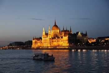 a sightseeing boat plying the danube at the Parliamnet at dusk