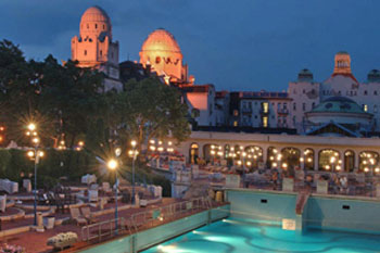 the outdoor pool and the dome sof the gellért bath and hotel at sunset