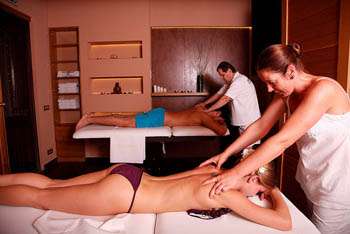 a massuer (man) massaging a young man, another massuer massaging a young lady