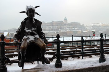 a bronze sttaue of a princess on a snowy day on the railing at the promenade