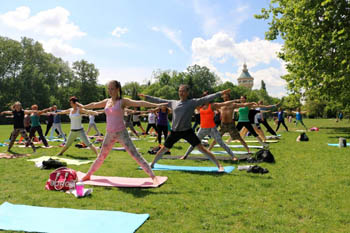 people doing yoga on a green lawn on a summer day