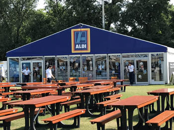 brown wooden tables and benches with an Aldi shop in the background