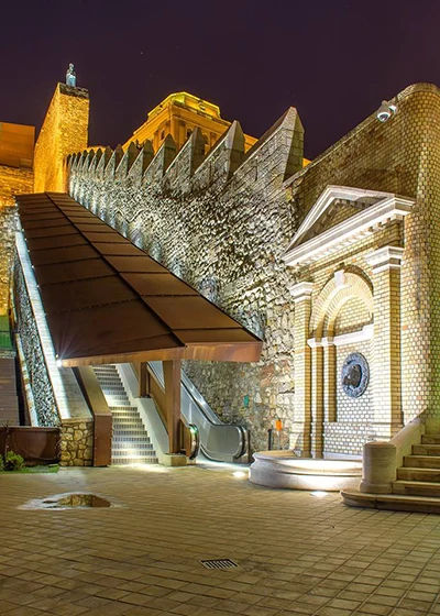 the covered escalator and stone steps leading up to the Royal Palace from the Castle Bazaar lighted up at night
