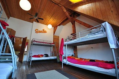 room with bunk beds and red blankets on them, wood paneled ceiling