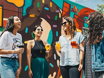 4 young women drinking beer and laughing, each of them holds a different kind of beer in her hand (dark, red, wheat etc..)