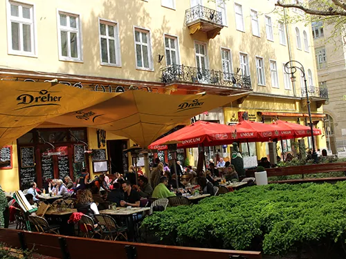 patrons sitting in the terrace of Cafe Vian under red or yellow shades