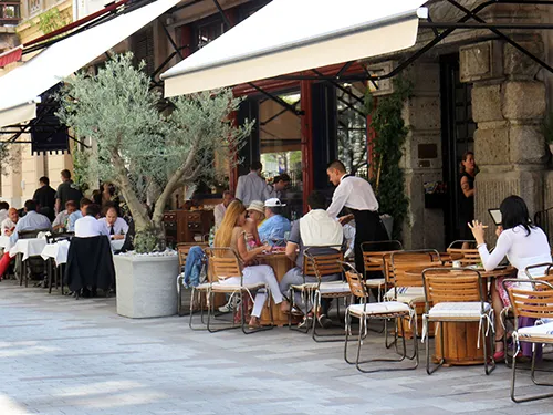 a waiter serving guests at a table on the terrace (possibly a restaurant on the Danube Promenade)