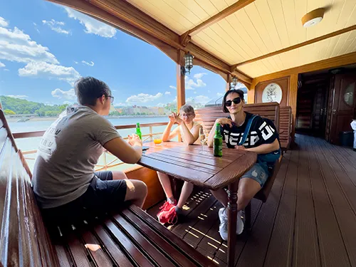 the author of this site with her two teenage sons sitting at a wooden table on the partially open deck of the Kisfaludy historic paddler