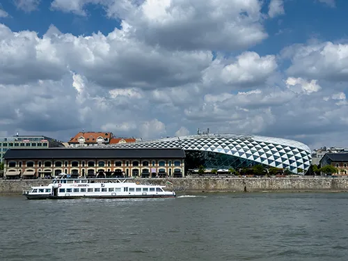 the Whale building as senn from a boat on the Danube (lots of ominous-looking clouds in the sky)