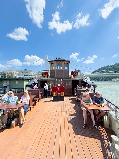 tourists sitting onboard the Kisfaudy historic steam boat in summer (the white Elizabeth bridge in the backgroun)